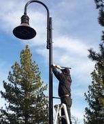 A man installing streetlight banners on a lamp post.
