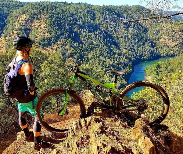 A biker looks over a river from a trail above