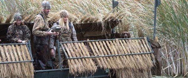 man and woman duck hunting in a duck blind