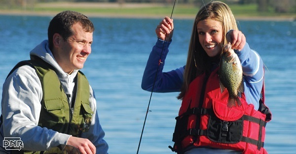 A couple fishing for fall crappie in a boat.
