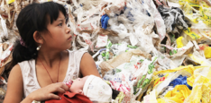 Image of young girl holding a baby surrounded by plastic garbage