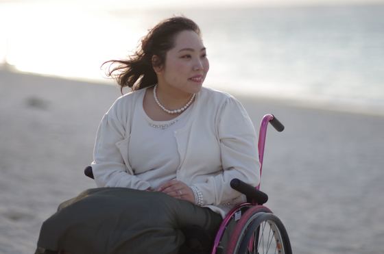 A woman sits in a wheelchair on the beach