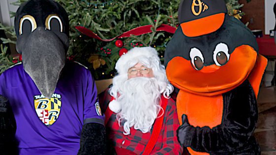 IMAGE: Santa Claus poses with the Oriole Bird and the Ravens' Poe mascots