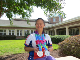 Young woman with Down Syndrome poses with medals outside