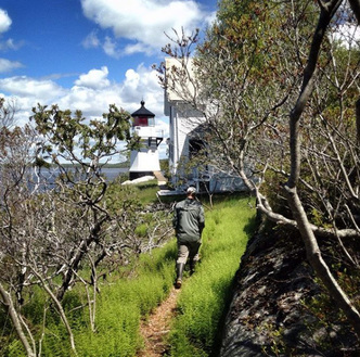 Hiker on trail beside historic lighthouse on Perkins Island.