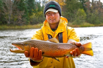DNR fisheries technician James Zellinger holds a brown trout, part of a recent mark-and-recapture research project.