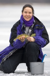 woman holding fish on the ice