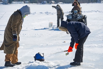 Young angler watches a sonar depth finder while ice fishing