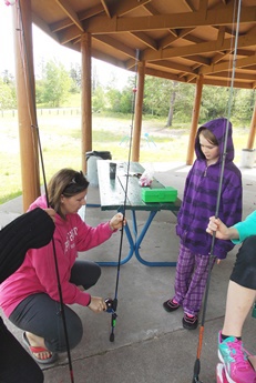 parent helping little girl with fishing pole