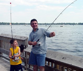 A child and an adult share a laugh while fishing in the summertime.