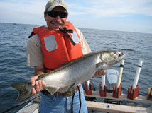 Angler holding a Chinook salmon on a boat on Lake Huron