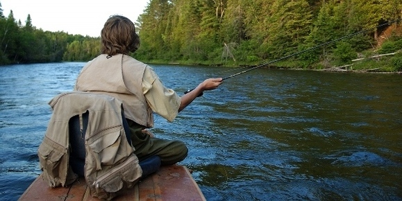 man fly fishing from boat on river