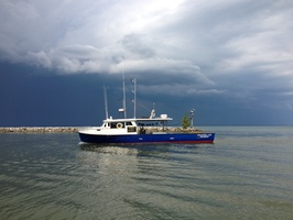 R/V Channel Cat out on water with dark clouds in background