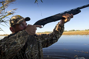 waterfowl hunter aiming shotgun