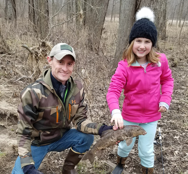Man and young girl holding a sucker they caught