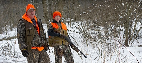 older man and young man hunting in winter woods