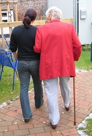 Younger woman and older woman walking together arm in arm