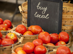 Tomatoes in baskets with sign that says "buy local"