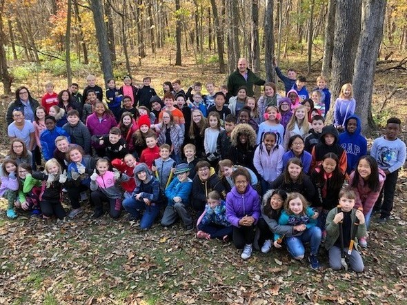 Several dozen 4th graders pose for a photo with their teachers in the woods they helped clear in Fairview Park. 