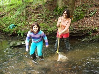 mom and daughter sampling stream quality