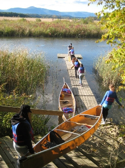 Girls carrying canoes out onto a dock
