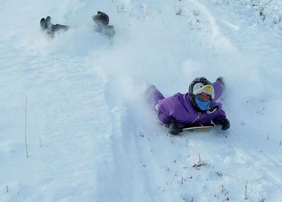 child sledding in snow
