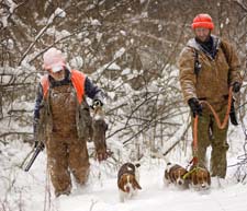 Hunters walking through the snow with dogs