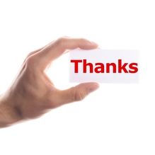 Hand holds small white card that simply has "Thanks" written in red on it 