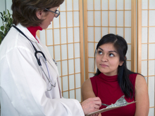 Female doctor discusses screening results with attentive, young, female patient.