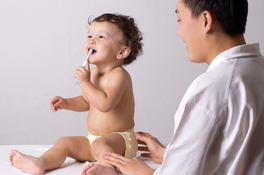 Happy baby tries to brush teeth during well-child visit