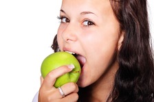 A girl eats a green apple.