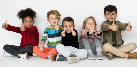 Five children smiling and giving the thumbs up sign to the camera.