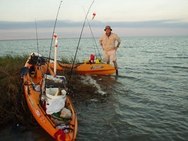 angler and two kayaks at water's edge