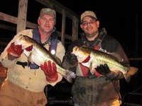 two anglers holding really big bass, nighttime