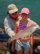 father and young daughter show a redfish