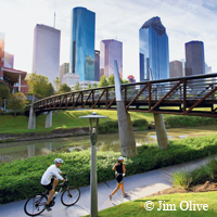 jogger, biker, riverside path, Houston skyline