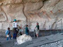visitors and park guide with rock art in cavern