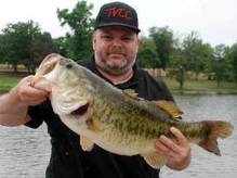 Man near water holding healthy 13 pound bass