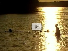 2 people playing in lake, sunset