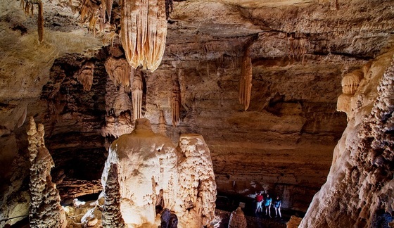 3 people touring Longhorn Cavern by the formation called "The Chandelier"