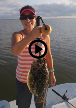 happy woman holding up large flounder, video link