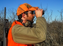 guy in blaze orange looking through binoculars
