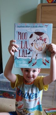Boy holding up Moo la la book
