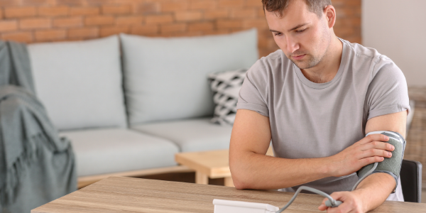 Young man sat taking his blood pressure at home