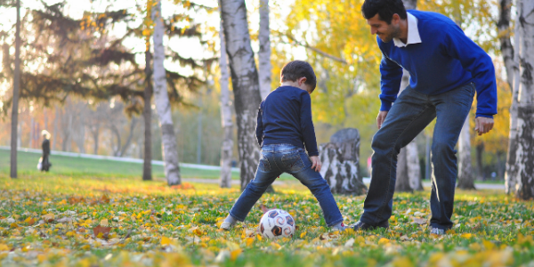 Dad and son playing football in an autumn park