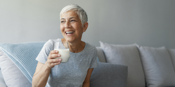Woman experiencing the menopause drinking a glass of milk and smiling