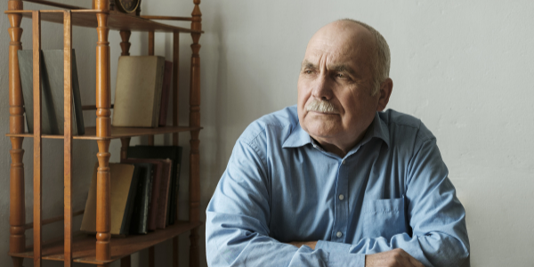 elderly man sat at home looking lonely into the distance