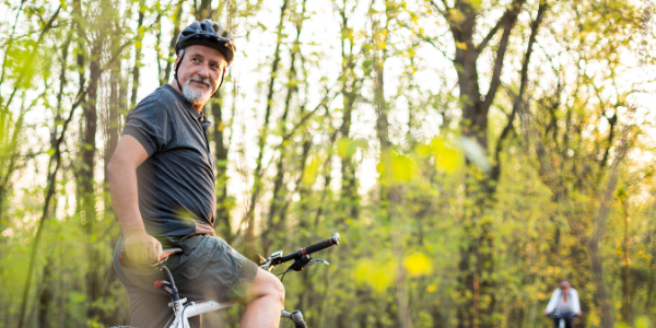 Man on pedal bike, looking over his shoulder in a forest in springtime