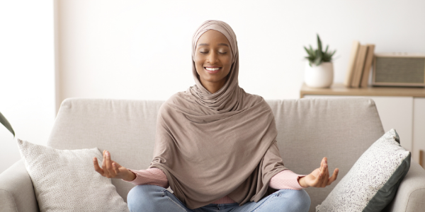 lady sat on sofa smiling in a sitting yoga position