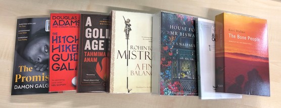 seven books lying in a row on a flat surface